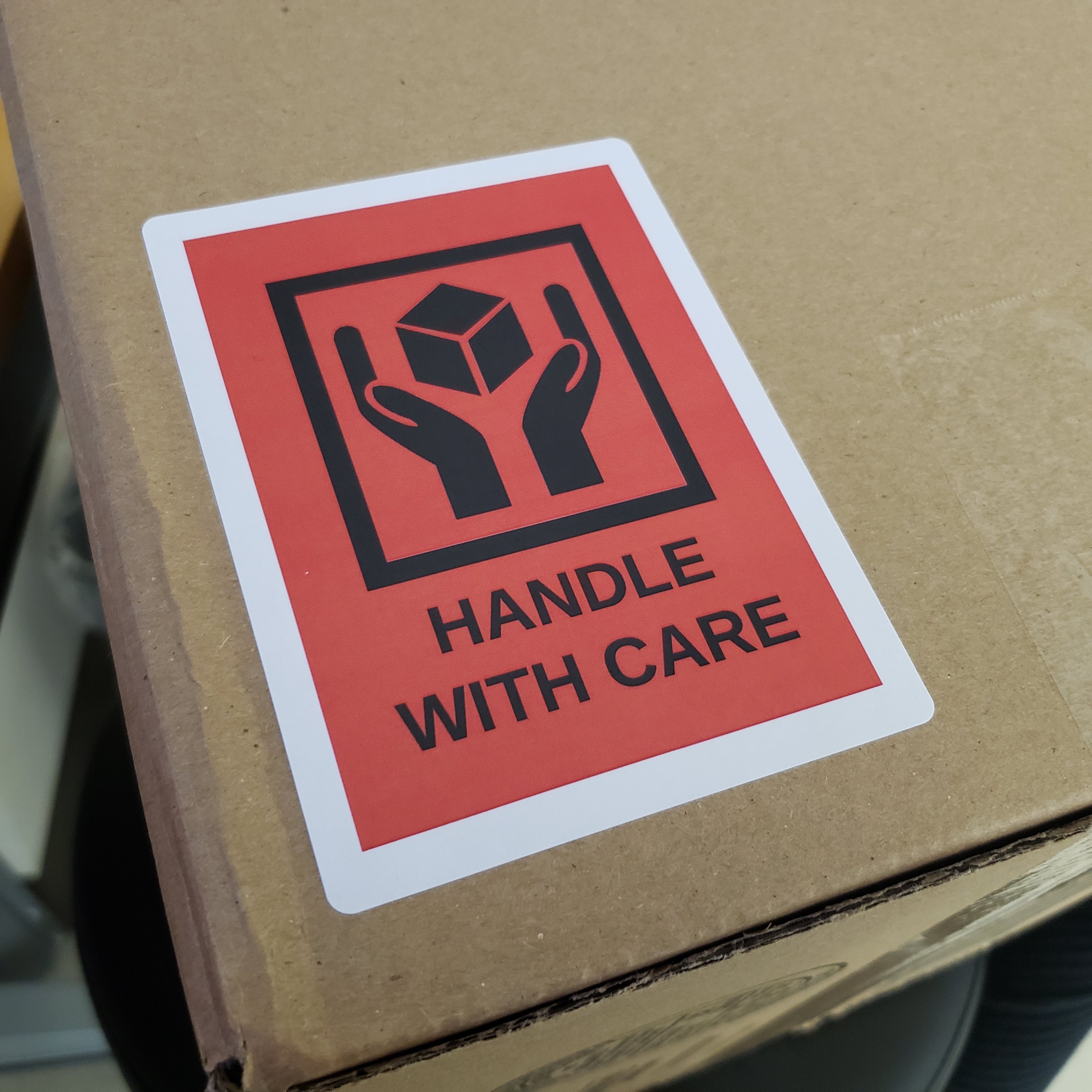 &quot;Handle with care&quot; shipping label design printed on 4" x 3" white matte labels, stuck to a cardboard shipping box