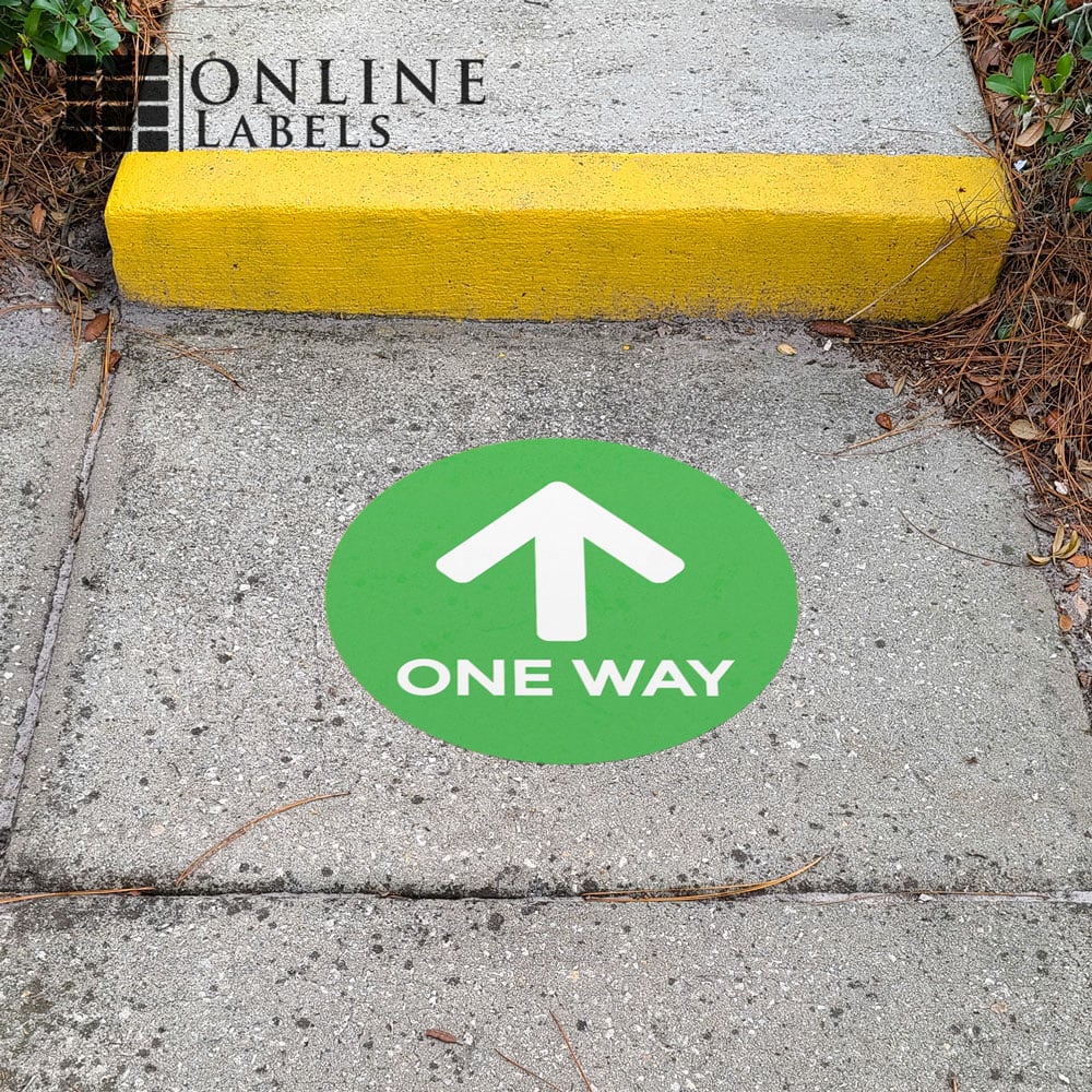 Green "one way aisle" floor sticker on sidewalk outside for directing guests during covid